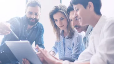 Groupe de personnes regardant une tablette.