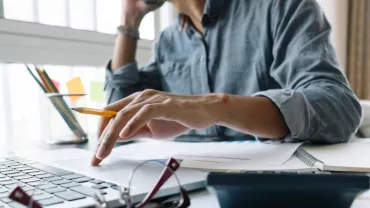 Personne travaillant sur un ordinateur portable avec des documents ouverts.