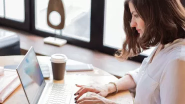 Personne travaillant sur un ordinateur portable à un bureau en bois.