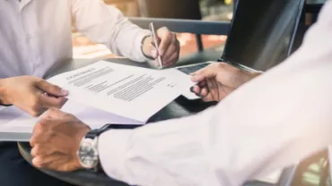 Deux personnes signent un document sur une table.