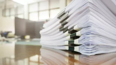 Pile de documents empilés sur une table en bois.